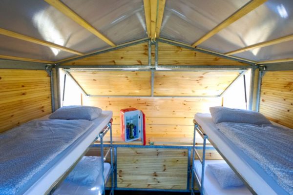 Cosy Event Lodge from inside with wooden panelling, two bunk beds with four mattresses and bedding