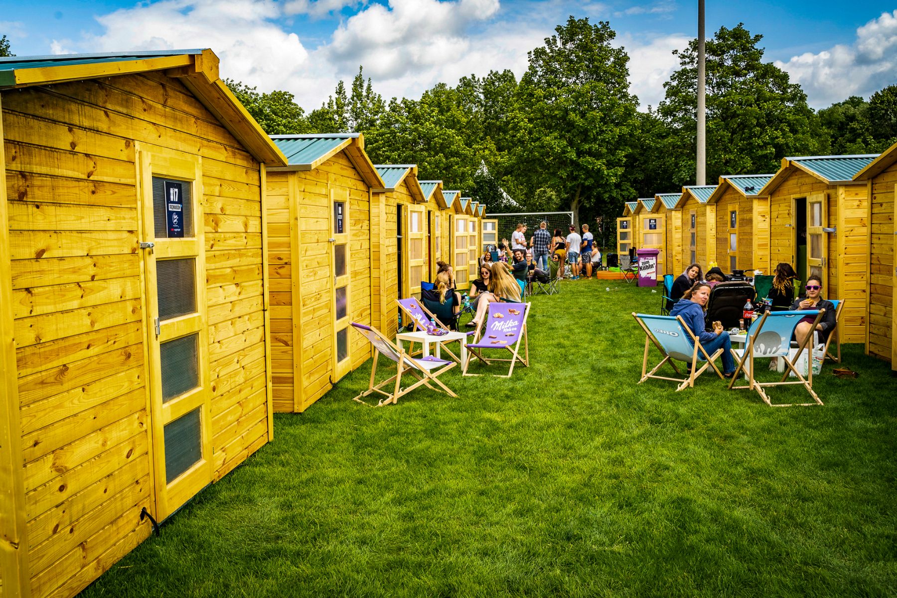 Cosy Event Lodge from outside, lined up with deck chairs and people
