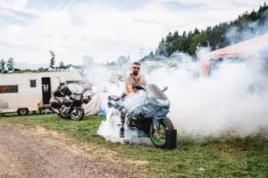 Camping guest accelerates on his motorbike and smoke rises